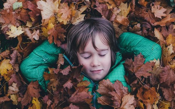 foto de menino deitado entre as folhas secas