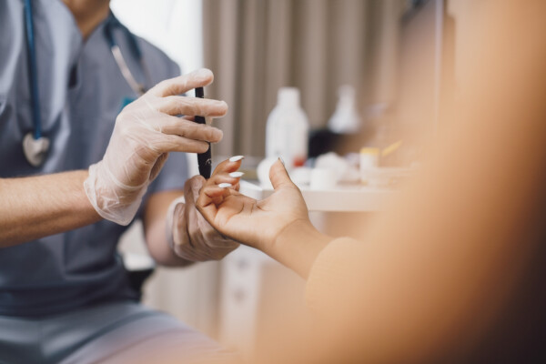 Imagem cortada de médico realizando teste de glicemia no dedo de uma mulher