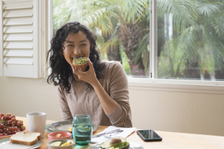 Mulher sorridente comendo abacate