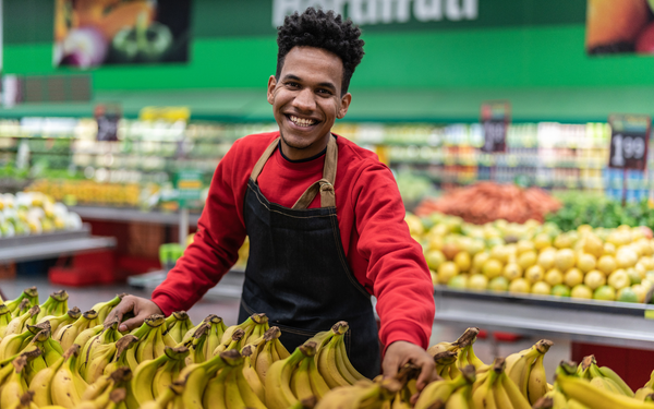 Homem jovem e sorridente trabalhando em supermercado