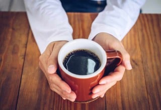 Pessoa segurando xícara vermelha com café.