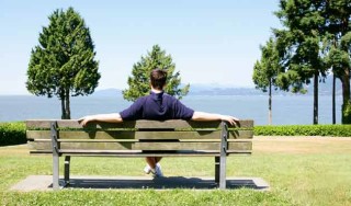 Homem sentado no banco de uma praça olhando a paisagem - Foto: Getty Images