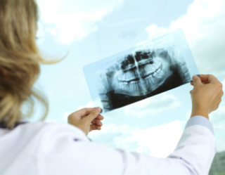Dentista analisando raiografia dentária de paciente