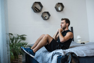Homem fazendo abdominais na cama - Foto:&nbsp;Shutterstock