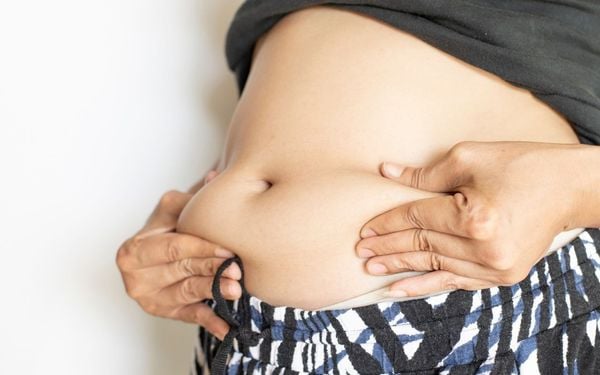 pessoa apertando a barriga inchada