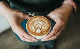 Close up de uma pessoa segurando uma xícara com café