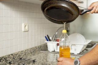 Pessoa colocando óleo reutilizável dentro de uma garrafa pet