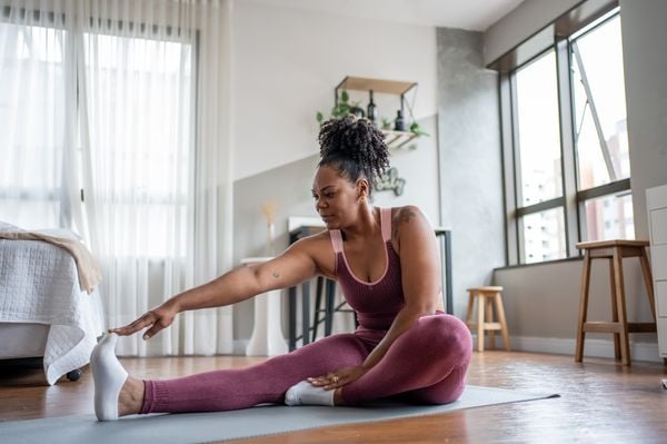 Mulher negra se alongando em casa