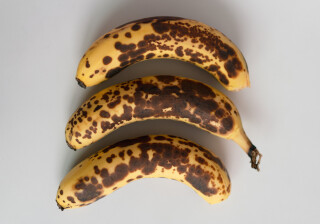 três bananas maduras alinhadas em um fundo branco