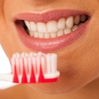 Mulher sorrindo mostra escova de dentes - Foto: Getty Images