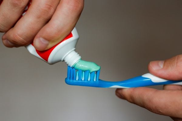 Close up de mãos masculinas colocando pasta de dente em uma escova dental