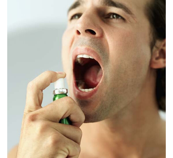 Homem aplicando spray na boca para diminuir o mau hálito