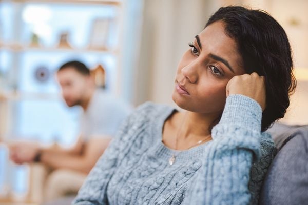 Mulher brava com homem que está ao fundo desfocado