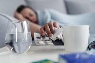 Mulher deitada no sofá pegando remédio para gripe