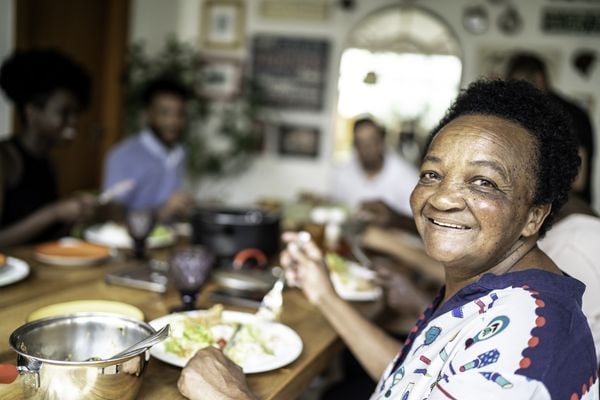 Mulher idosa sorrindo enquanto almoça em família