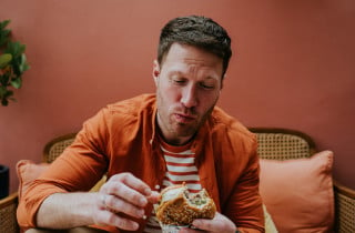 Homem comendo um hamburguer