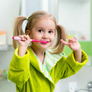 Criança com escova de dentes mostrando que está fazendo a higienização bucal - Foto: Getty Images