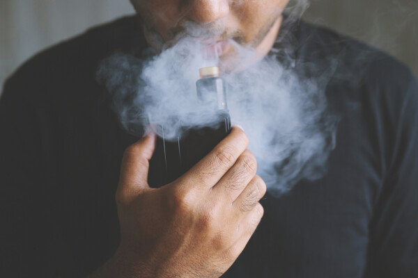 Foto aproximada de homem fumando cigarro eletrônico