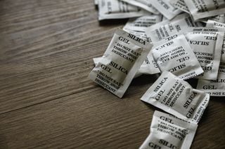 Diversos sachês de silica em gel sobre mesa de madeira