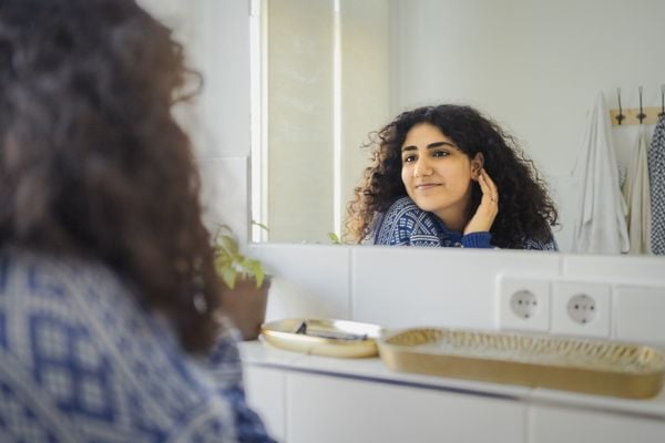 Mulher sorrindo para si mesma em frente ao espelho