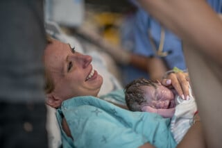 Mulher segurando o filho logo após o parto