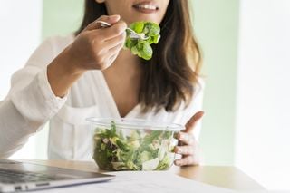 Mulher comendo uma tijela de salada de folhas verdes