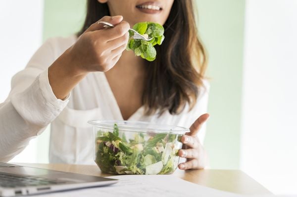 Mulher comendo uma tijela de salada de folhas verdes