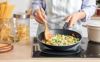 mulher cozinhando arroz na frigideira