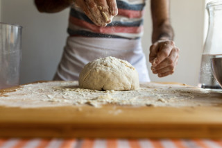 homem espalhando farinha em massa de pão