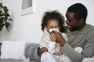 Pai limpando nariz de filha doente