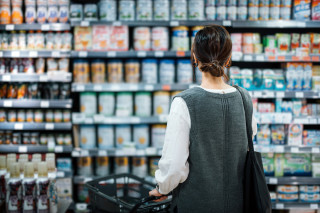 Mulher no supermercado em frente a estante de produtos