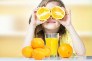 Menina brinca colocando duas fatias de laranja no lugar dos olhos - "Foto: Getty Images"