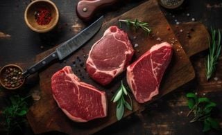 Três cortes de carne cruas em uma tabua de madeira