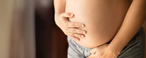 Close up da barriga de uma gestante, que tem as mãos apoiadas na barriga