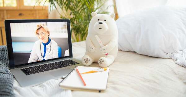 Ursinho de pelúcia ao lado de um notebook aberto com o vídeo de uma ginecologista