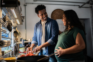 Homem cozinhando para a esposa grávida