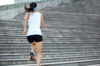 Mulher de costas subindo escadas enquanto se exercita