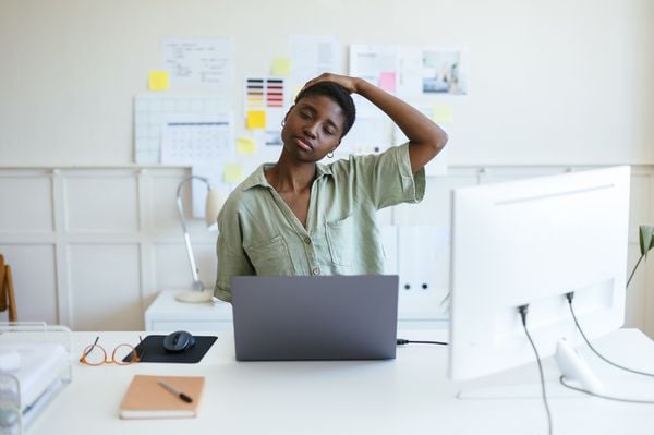 Mulher fazendo alongamento de pescoço enquanto trabalha