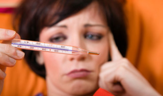 mulher com febre segurando o termômetro - Foto Getty Images