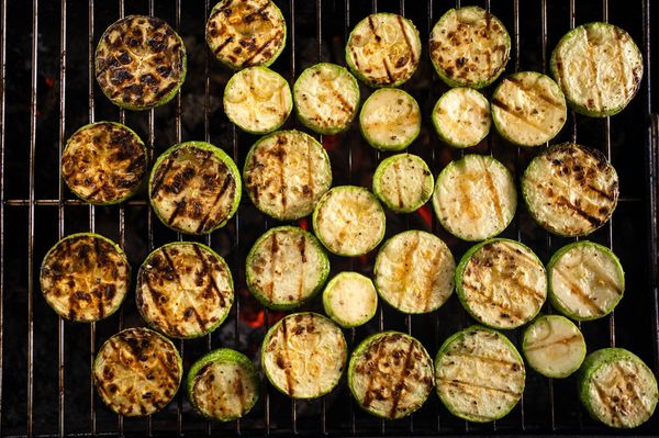 Grelha de churrasco com diversas rodelas de abobrinha