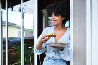 Mulher negra segurando um prato com avocado toast