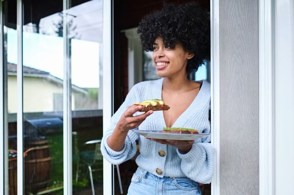 Mulher negra segurando um prato com avocado toast