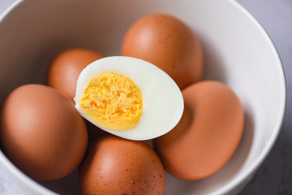 Ovos em uma tigela. Um ovo está em foco, cozinho e partido no meio