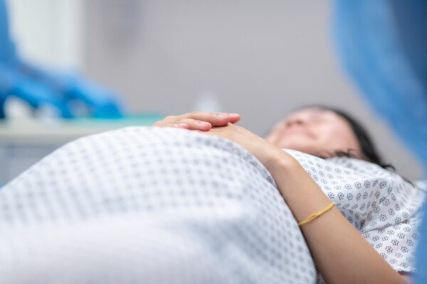 Mulher deitada na cama com roupa hospitalar