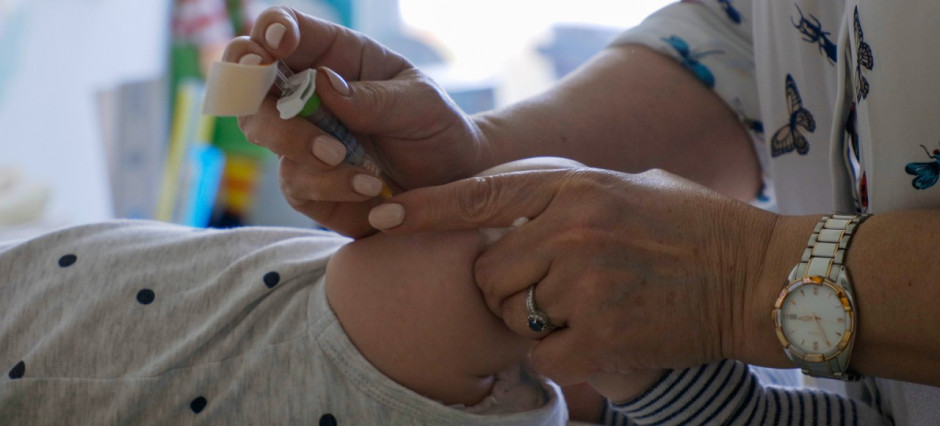 Enfermeira aplicando vacina na perna de bebê