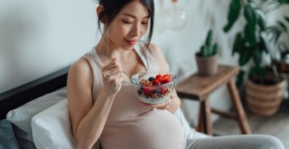 Mulher grávida comendo pote com frutas e iogurte