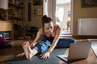 Mulher se exercitando no chão de frente à um computador
