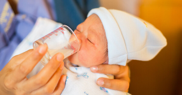 Bebê tomando leite do copo