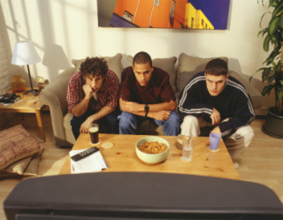 Homens comendo enquanto assistem televisão 