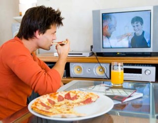 homem assistindo tv e comendo uma pizza
